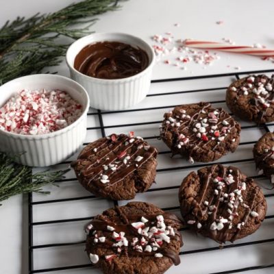 Gluten-Free Peppermint Chocolate Cookies with Crushed Candy Canes on Top Cooling on Baking Rack on Festively Decorated Counter Top