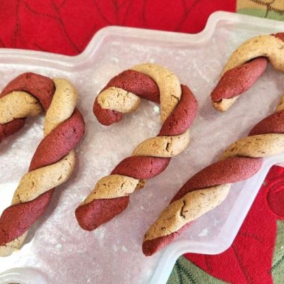 Close-up of Canine Candy Canes: Homemade Peanut Butter Dog Treats in Christmas Tree-Shaped Dish on Festive Tablecloth