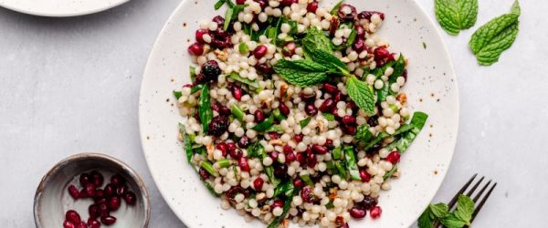 Festive Pomegranate Couscous Salad with Mint, Spinach and Cranberries on Stoneware Plate