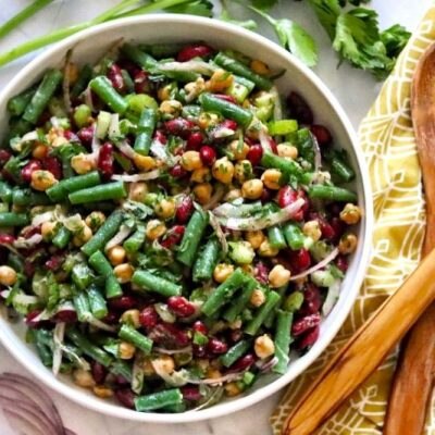 Three Bean Salad in Round Bowl With Wooden Serving Utensils Next to It on Pretty Kitchen Towel