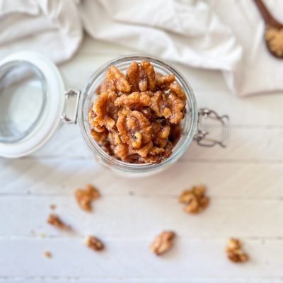 An Overhead View of Glossy Vegan Candied Walnuts Overflow from a Glass Jar.