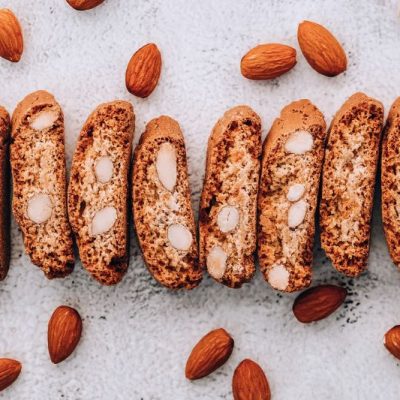 Italian Almond Biscotti Laid Out in a Line on a Plate Surrounded by Whole Raw Almonds