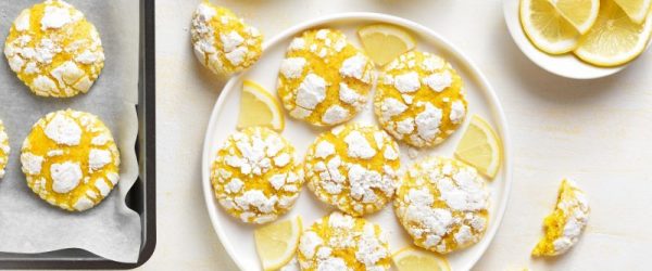 Lemon Crinkle Cookies Dusted in Powdered Sugar Set on Plate with Lemon Slices