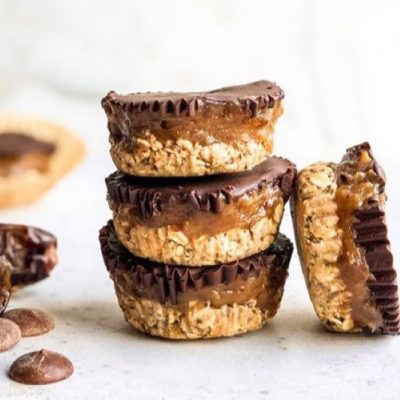 Vegan Date Caramel Chocolate Cups Stacked Up on A Counter Strewn With Cacao Wafers and Dates