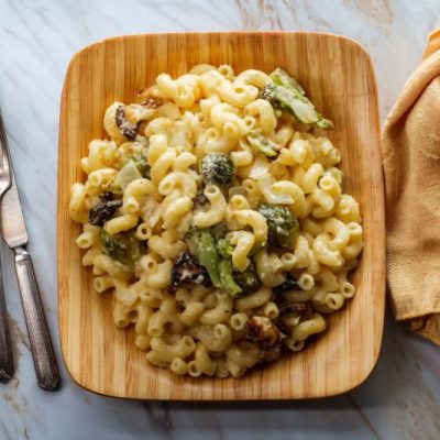 A Bamboo Bowl of Vegan Mac and Cheese with Broccoli Florets Set Atop a Marble Counter