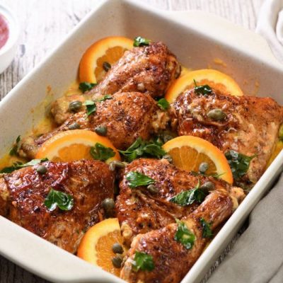 Baked chicken in a sauce with oranges and capers in a baking dish