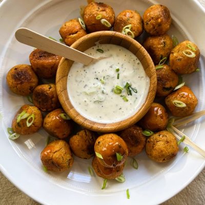 A Serving Plate is Filled With Buffalo Chickpea Meatballs With a Smaller Bowl of Ranch Dressing for Dipping.