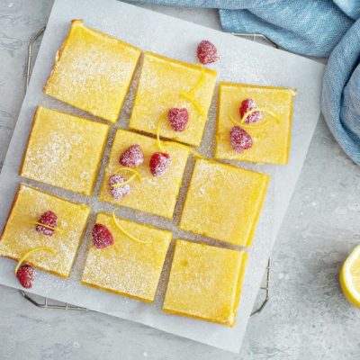 Sliced Squares of Lemon Bars on Serving Board With Raspberries on Top