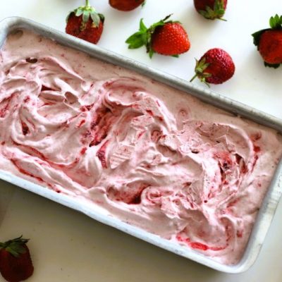 Strawberries & Cream Dairy-Free Ice Cream in a Loaf Pan on a White Background Strewn with Strawberries