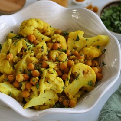 A Bowl of Chickpea Curry With Cauliflower is Garnished With Parsley.