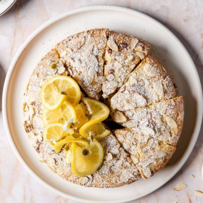 Round Almond-Topped Lemon Coconut Cake Sliced Like a Pie on a Round Serving Plate