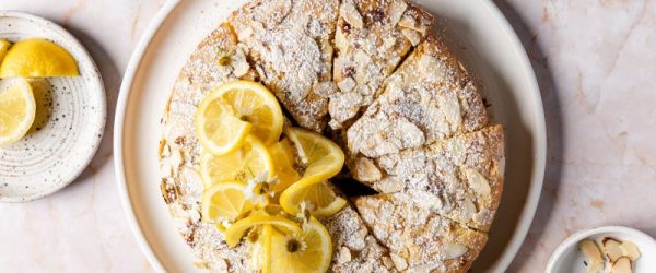 Round Almond-Topped Lemon Coconut Cake Sliced Like a Pie on a Round Serving Plate