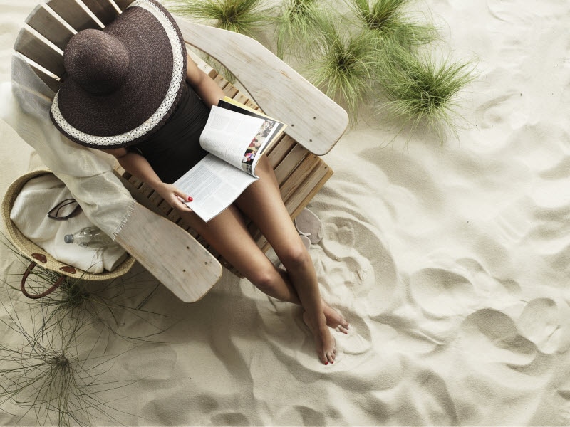 Overhead View of Woman Wearing Brown Sun Hat at Beach to Represent Stress Free Travel Concept