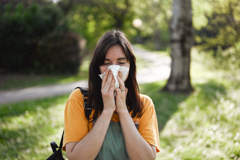 Concept of Gut Health and Allergies Represented by Woman Blowing Nose in Park