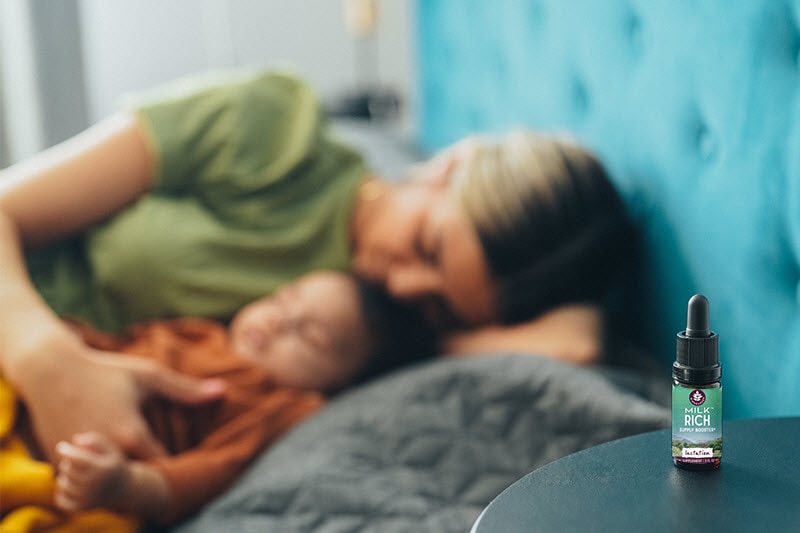 Mother and Baby Sleeping in Bed With Bottle of Holistic Remedies for Breastmilk on Nightstand