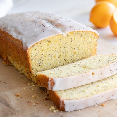 A Lemon Poppyseed Loaf Made with Einkorn Flour is Sliced and on a Cutting Board.