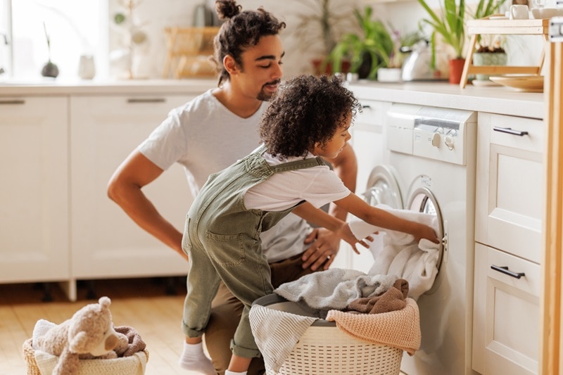 12 Natural Laundry Products That Really Work A Father and Son Unload the Dryer Together, Representing Natural Laundry Products.