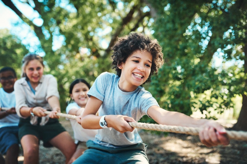 Group of Happy Kids Playing Tug O' War to Represent Concept of the Benefits of Summer Camp