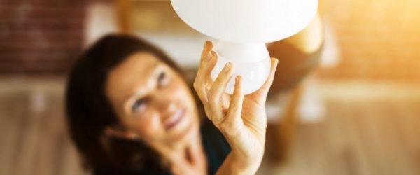 Overhead View of Woman Screwing in Lightbulb on Hanging Lamp to Represent Concept of Are LED Lights Bad for You