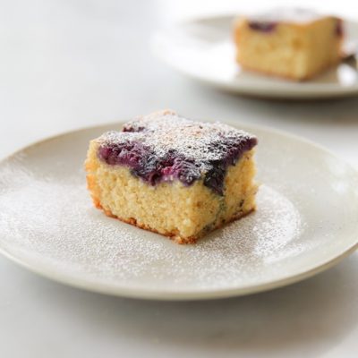 A Slice of Blueberry Yogurt Cake Made With Einkorn Flour Sits on a Small, White Cake.