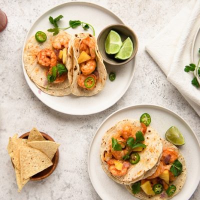 Four Small Plates Have Individual Servings of Grilled Shrimp Tacos With Fresh Lime, Sliced Jalapeno and Cilantro.