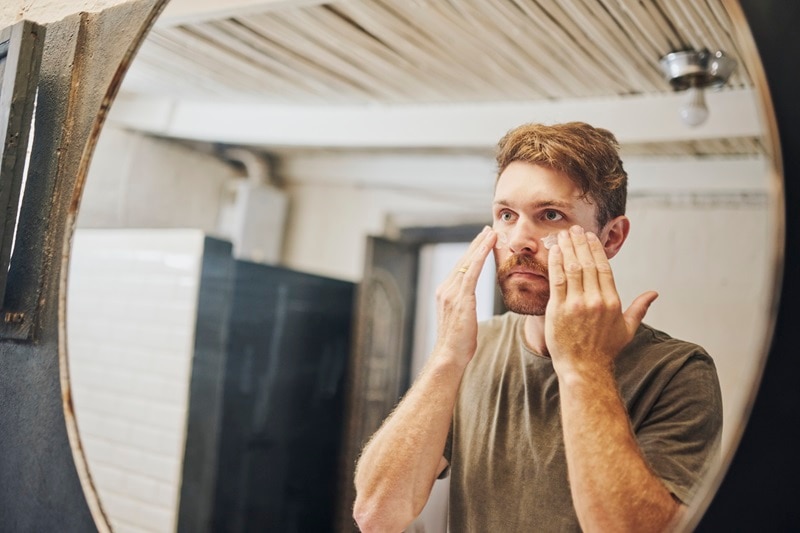 A Man Applies Sunscreen to His Face, Representing the Question, "How Often to Reapply Sunscreen."