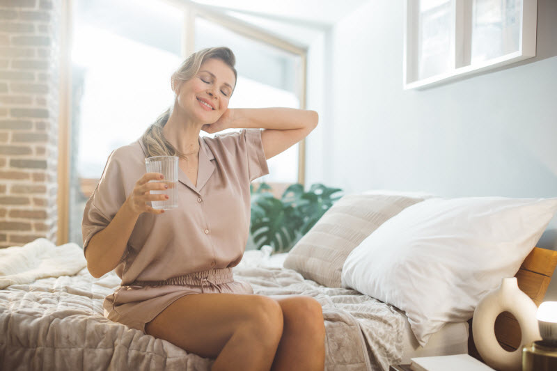 Content-Looking Woman Happily Sitting on Bed After Learning How to balance Estrogen Levels Naturally