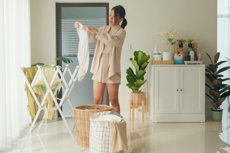 A Young Woman Hangs Laundry to Dry, Representing How to Wash Workout Clothes.
