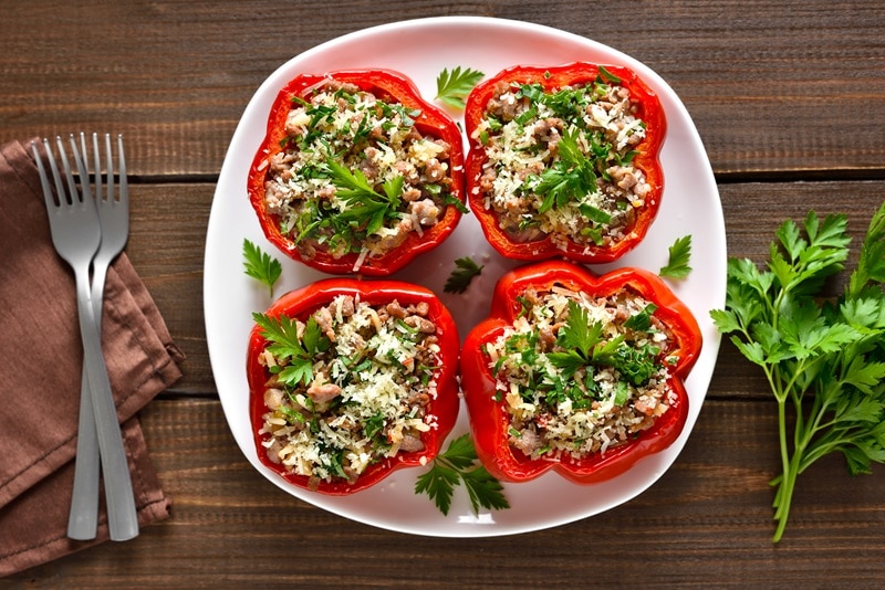 Four Lentil Stuffed Peppers Are Topped With Fresh Sprigs of Parsley.