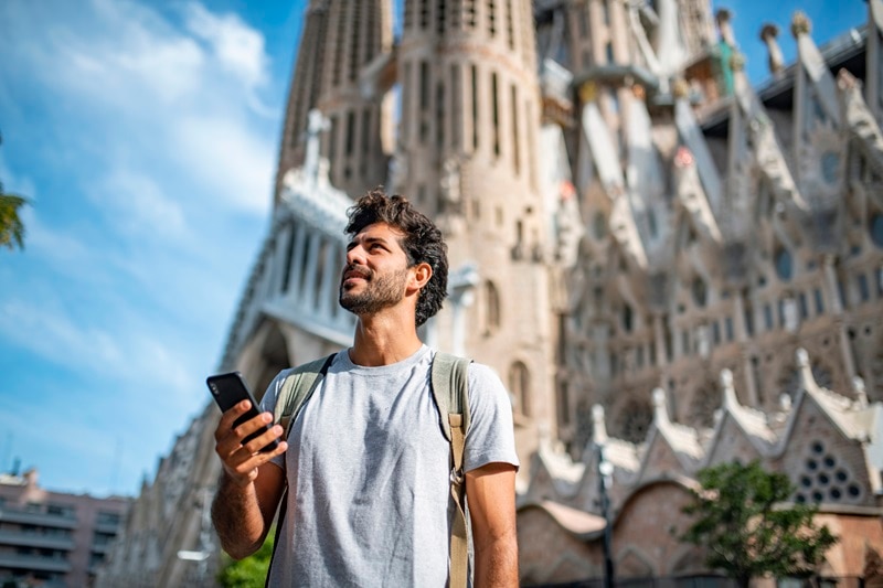 A Male Tourist Stands in Front of a Cathedral, Representing Travel and Stomach Troubles, Specifically the Question "What Causes Stomach Problems?"