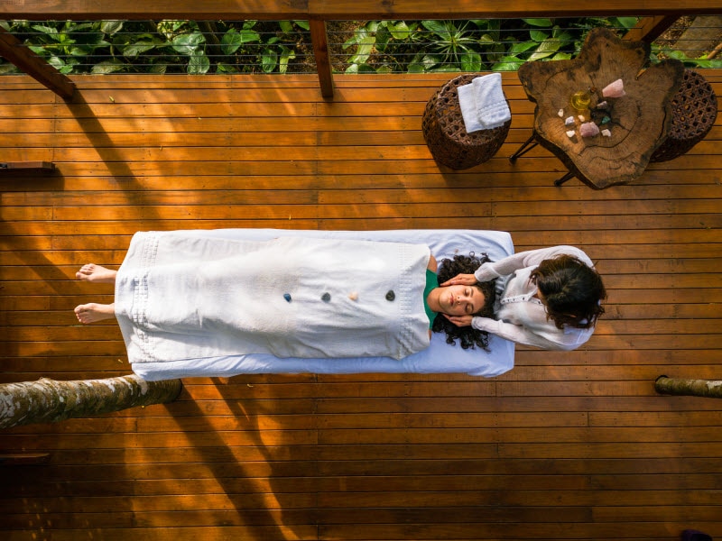 Concept of What is Reiki Represented by Overhead View of Woman Performing Energy Healing on Woman on Outdoor Deck