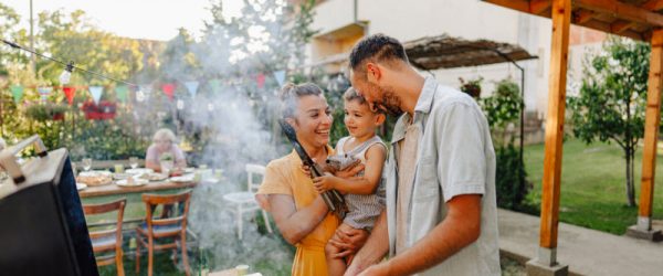 Young Family Grilling Corn in Backyard to Represent Concept of Charcoal vs Gas Grill Impacts on Health and the Environment