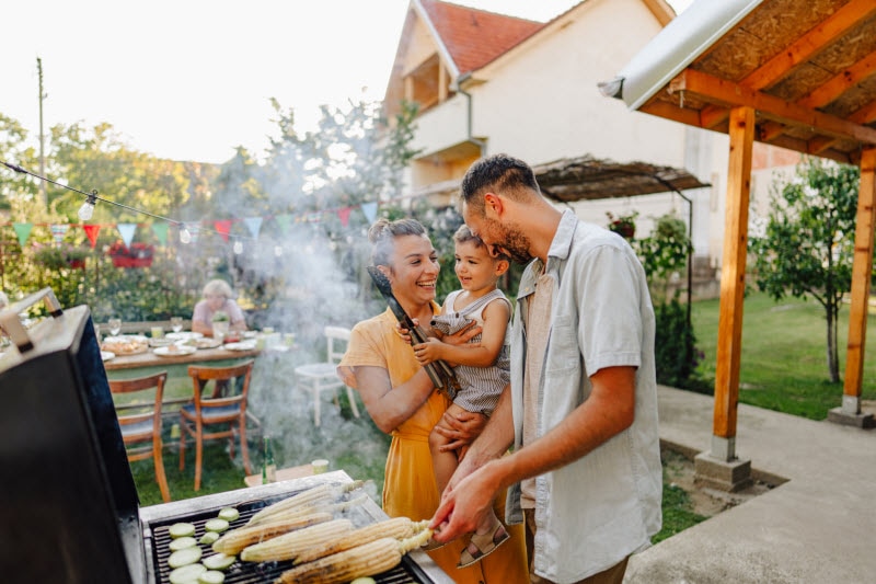 Young Family Grilling Corn in Backyard to Represent Concept of Charcoal vs Gas Grill Impacts on Health and the Environment