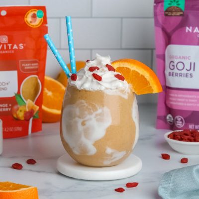 Orange Creamsicle Shake with Orange Slice, Goji Berries and Blue Straws Poking Out of Glass