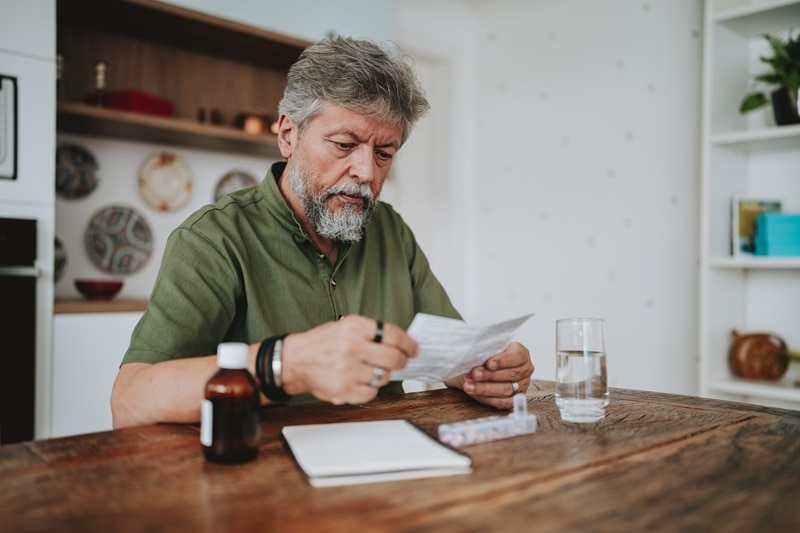 A Man Checks His Prescription, Representing Food and Medication Interactions.