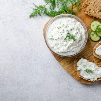 A Small Bowl of Dairy Free Tzatziki Sauce is Topped With a Fresh Sprig of Dill.