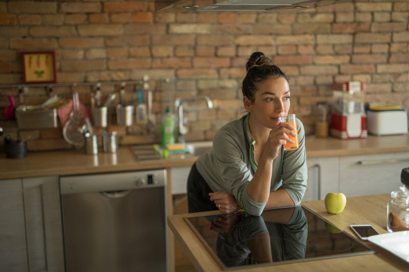 Woman Leaning Over Kitchen Counter Drinking Psyllium Husk Weight Loss Beverage