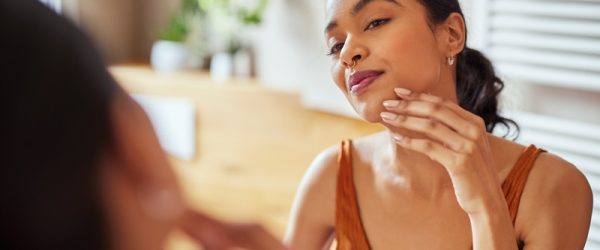 A Woman Checks Her Skin in the Mirror, Representing a Skincare Plateau.