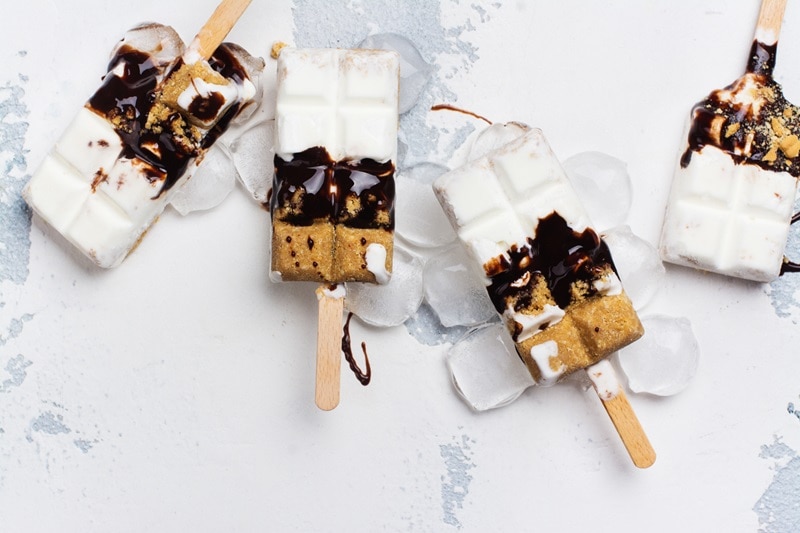 Four Homemade S'mores Ice Cream Pops Are Layered With Vanilla Ice Cream, Graham Cracker and Chocolate.