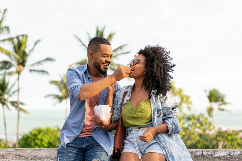 Couple on Boardwalk Near Beach Eating Popcorn to Represent Concept of Summer Heat and Gut Issues