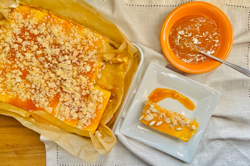 A Dish of No-Bake Tropical Cheesecake Bars is Covered in Passionfruit Jam and Sprinkled With Coconut Flakes.
