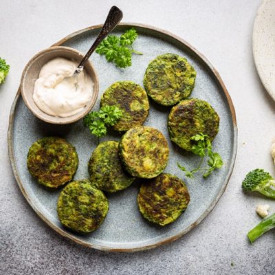 A Light Blue Plate Has Eight Vegetable Fritters With a Side of Creamy Dipping Sauce.