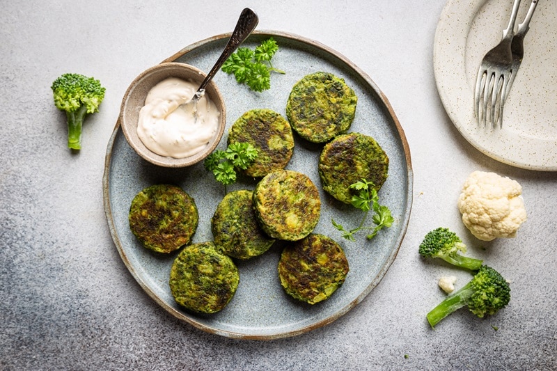 Vegetable Fritters A Light Blue Plate Has Eight Vegetable Fritters With a Side of Creamy Dipping Sauce.