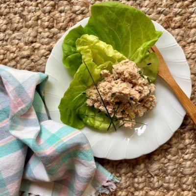 Salmon Salad on Bed of Lettuce on a Plate With Scalloped Edges. A Soft Napkin Lies Nearby.
