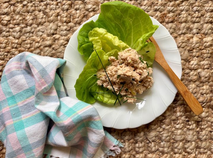Salmon Salad on Bed of Lettuce on a Plate With Scalloped Edges. A Soft Napkin Lies Nearby.