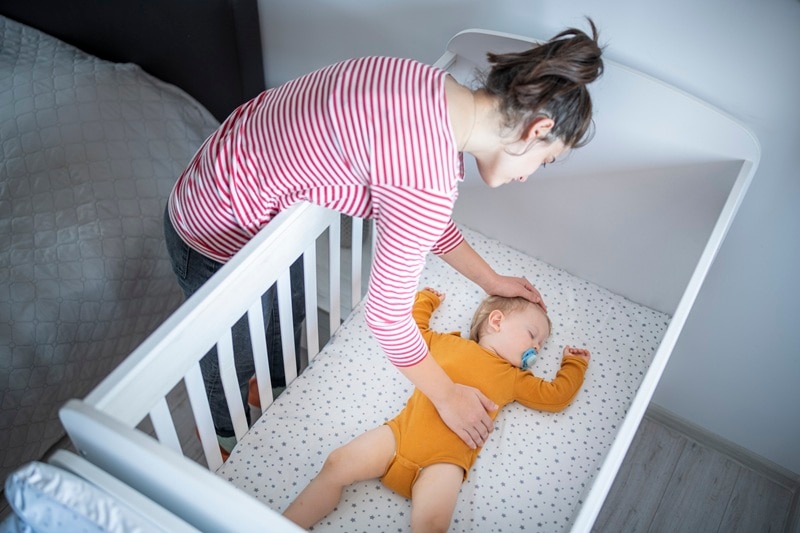 A Mother Calms Her Baby to Sleep in the Crib, Representing a Baby Bedtime Routine