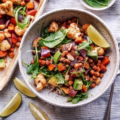 A Sweet Potato Sheet Pan Dinner Includes Roasted Chickpeas, Cauliflower and Red Onions and is Topped With Fresh Basil, Avocado and a Wedge of Lime.