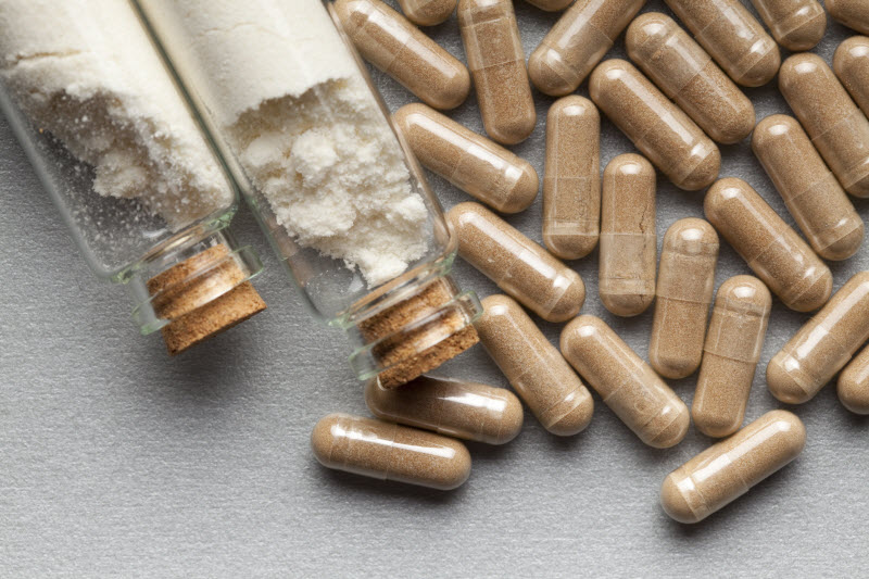 Concept of Tac in Vitamins Represented by Capsules on Gray Surface with Two Glass Bottles of White Powder