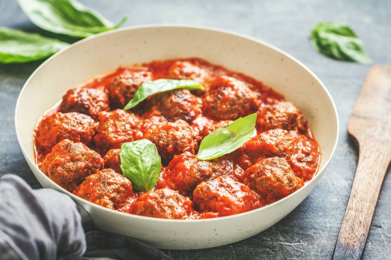 Homemade Turkey Meatballs in Marinara Sauce in a Round Bowl on a Slate Countertop, the Top is Dotted with Fresh Basil Leaves