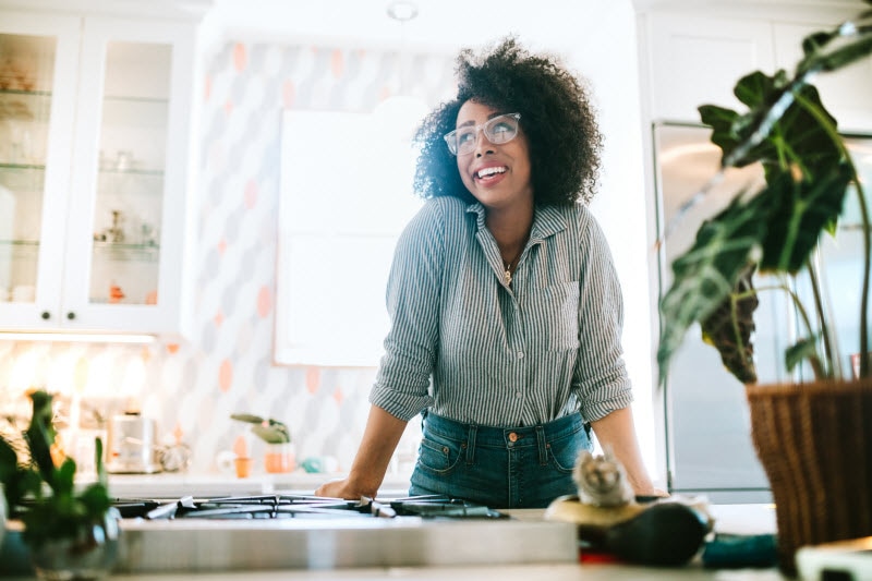 Smiling Woman Standin gat Kitchen Counter Happy Because She's Not Listening to Common Menopause Myths
